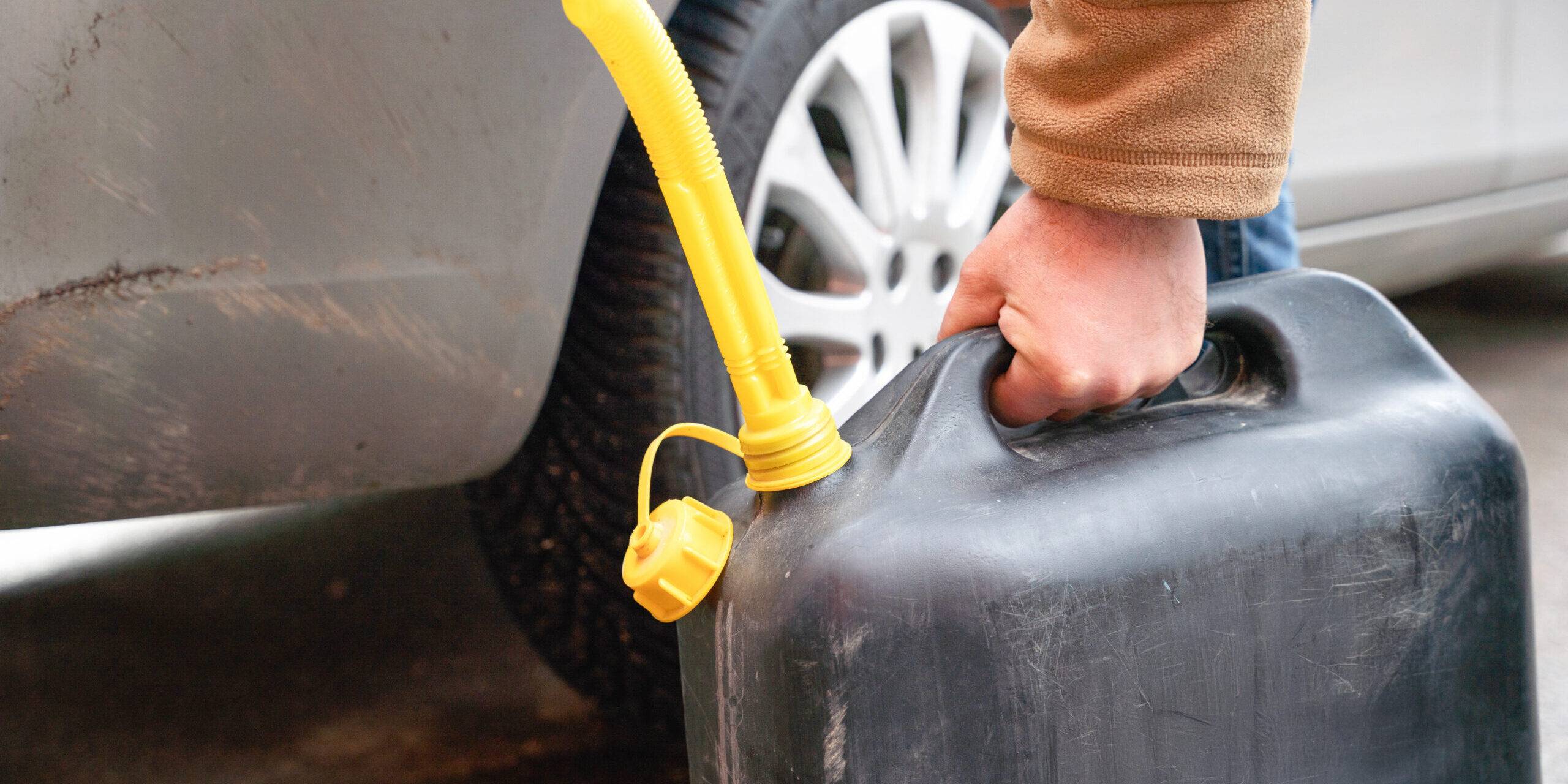 Person Filling Vehicle With Fuel From Portable Canister On Roadside Person Filling Vehicle With Fuel From Portable Canister On Roadside